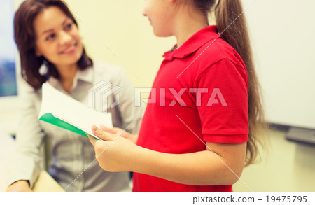 school girl with notebook and teacher in classroom school girl with notebook and teacher in classroom 19475795