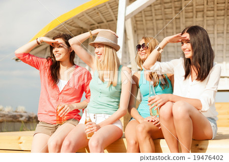 smiling girls with drinks on the beach smiling girls with drinks on the beach 19476402