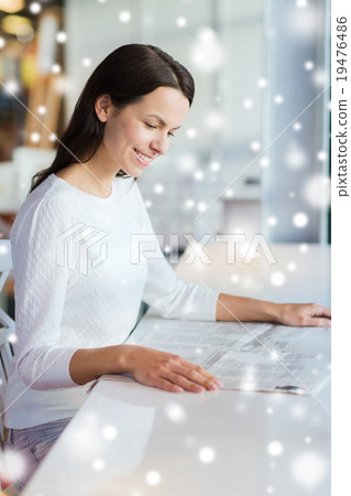 smiling young woman reading newspaper at cafe smiling young woman reading newspaper at cafe 19476486