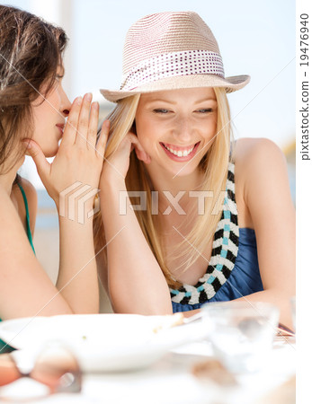 girls gossiping in cafe on the beach 19476940
