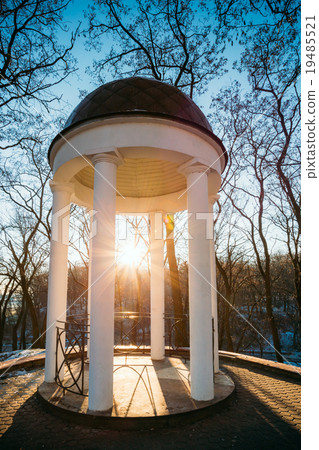 Sun at sunset shining through gazebo in city park 19485521