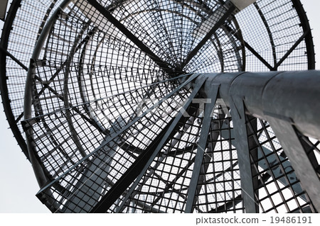 Metal spiral ladder, black silhouette over sky 19486191
