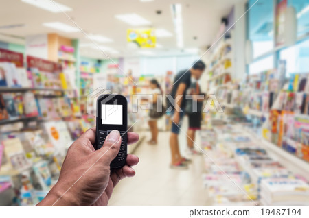 Phone white screen in hand on blurred book store 19487194