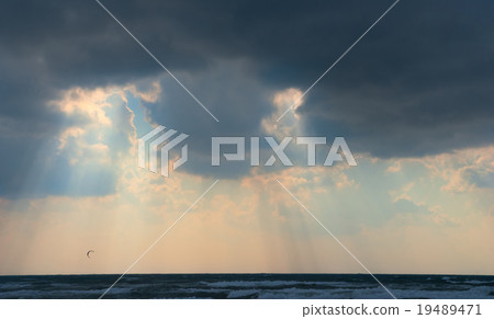 Sun behind dark storm clouds over the sea 19489471