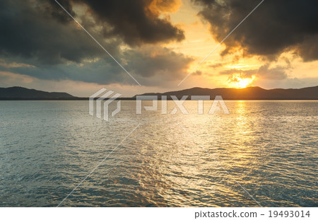 sunrise behind island in the sea 19493014