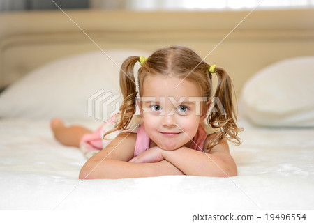 Little girl on the bed at home among the pillows Little girl on the bed at home among the pillows 19496554
