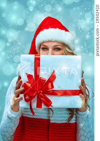 Girl dressed in santa hat with a Christmas gift Girl dressed in santa hat with a Christmas gift 19502410