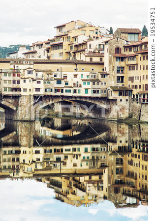Ponte Vecchio and historic buildings are mirrored in the river A 19534751
