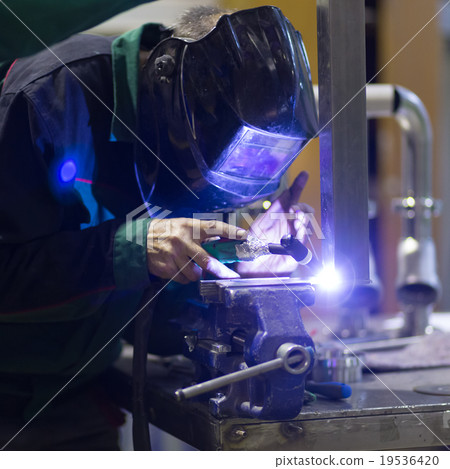 Industrial worker welding in metal factory. 19536420