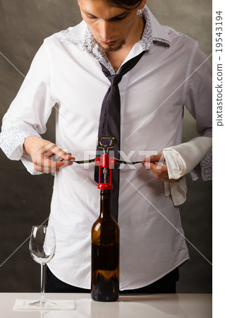 Man opening bottle of wine with corkscrew 19543194