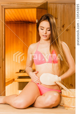Woman in sauna with exfoliating glove. Skincare. Woman in sauna with exfoliating glove. Skincare. 19543695