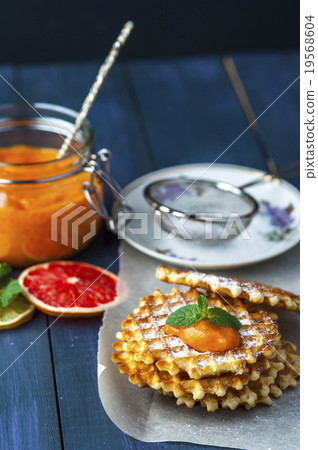 Wafers on baking paper with a jar of persimmon jam 19568604