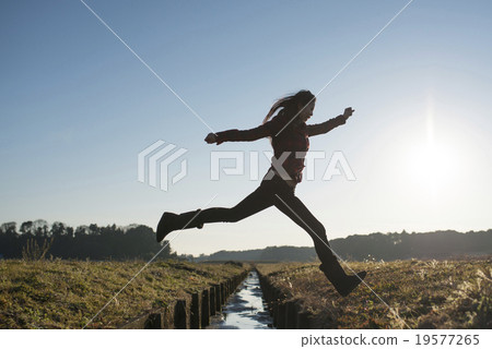 A woman who jumps over a waterway 19577265