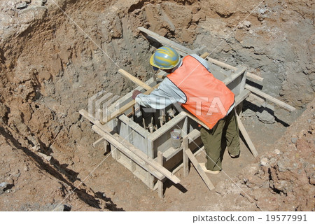 Construction workers installing pile cap form work Construction workers installing pile cap form work 19577991