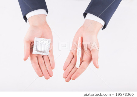 Male hands revealing condom and pregnancy test.  19578360