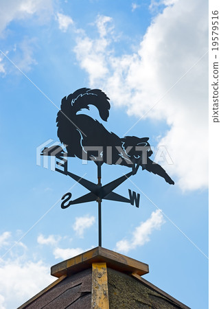 Weather vane on background of blue sky and clouds. 19579516