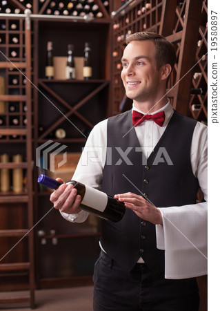 Attractive male winehouse worker is serving a Attractive male winehouse worker is serving a 19580897