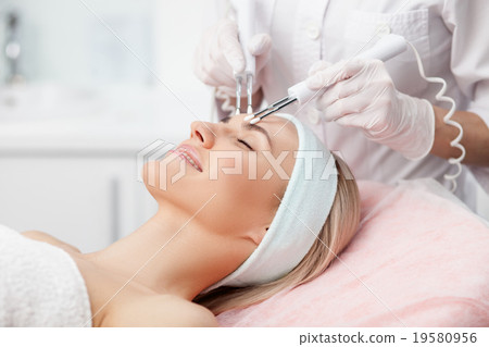 Cheerful female therapist is curing human skin 19580956