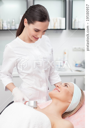 Attractive young beautician is treating her 19580957