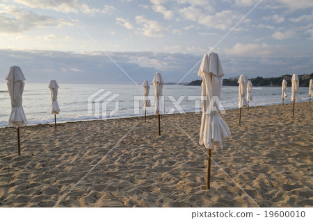 Beach umbrella on deserted coast sea at sunrise 19600010
