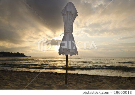 Beach umbrella on deserted coast sea at sunrise Beach umbrella on deserted coast sea at sunrise 19600018