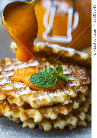 Wafers on baking paper with a jar of persimmon jam 19608249