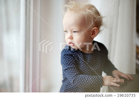 Adorable toddler girl looking through the window 19610735