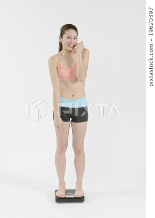 一個年輕女子在規模上擺出姿勢 19620397