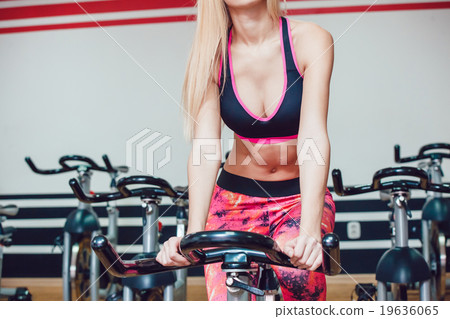 Young blonde woman on a stationary bike. Young blonde woman on a stationary bike. 19636065