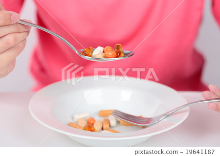 Young women eating medicine capsules on spoon. Young women eating medicine capsules on spoon. 19641187