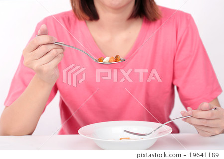 Young women eating medicine capsules on spoon Young women eating medicine capsules on spoon 19641189