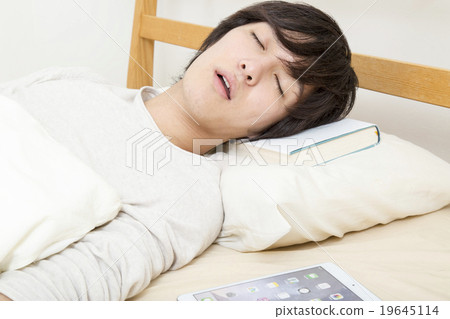 A young man sleeping on a pillow with a book 19645114