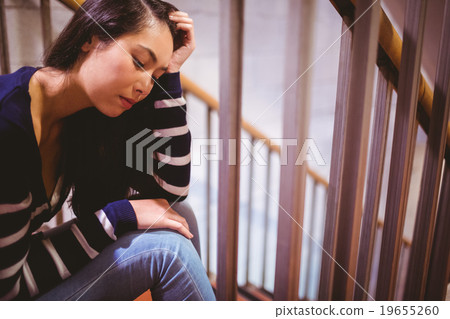 Worried student sitting in hallway 19655260