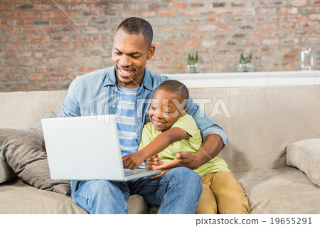 Father and son using laptop on the couch Father and son using laptop on the couch 19655291