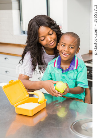 Smiling mother preparing sons school lunch Smiling mother preparing sons school lunch 19655712