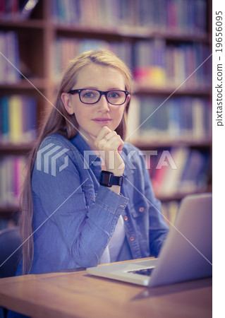 Student with smartwatch using laptop in library 19656095