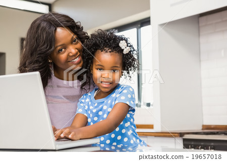 Daughter using laptop with mother  19657018