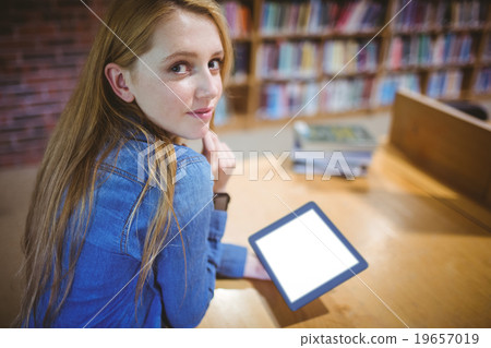 Student using tablet in library looking back at the camera 19657019