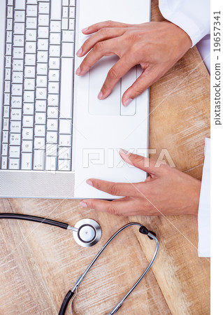 Doctor using laptop on wood desk  19657341