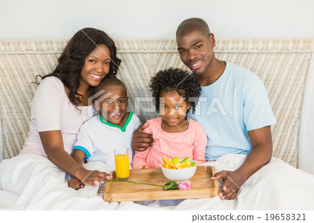 Happy family having breakfast in bed together Happy family having breakfast in bed together 19658321