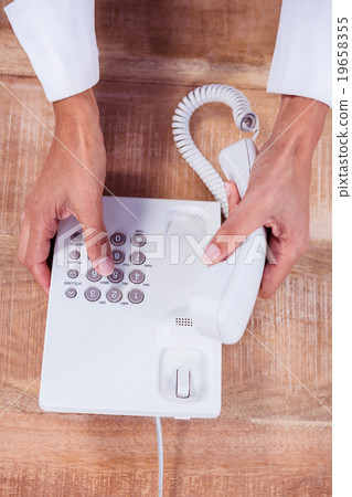 Businesswoman holding a phone at her desk 19658355