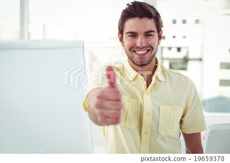 Smiling creative businessman by his desk Smiling creative businessman by his desk 19659378