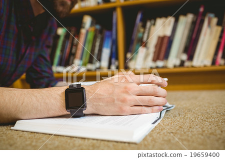 Student studying on floor in library wearing smart watch 19659400