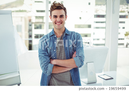 Smiling creative businessman by his desk Smiling creative businessman by his desk 19659499