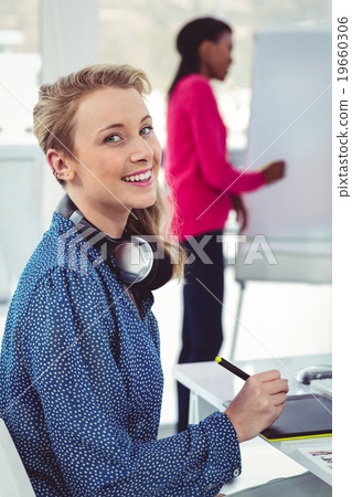 Graphic designer wearing headphones at desk Graphic designer wearing headphones at desk 19660306