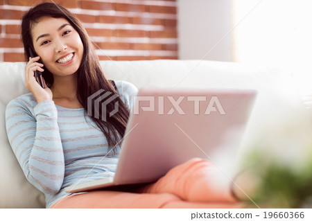 Asian woman on the phone using laptop 19660366