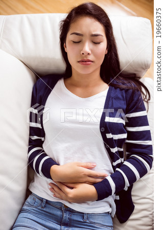 Asian woman lying on the couch with cramps 19660375