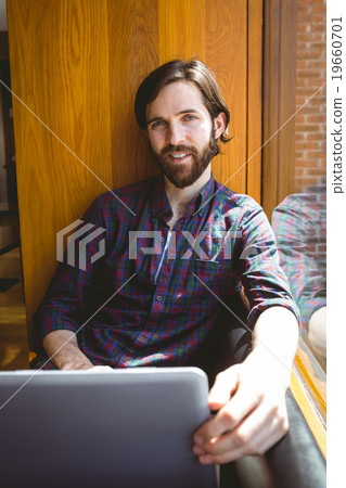 Hipster student using laptop in canteen 19660701