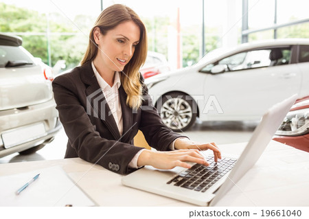 Smiling saleswoman typing on her laptop 19661040
