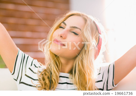Pretty blonde listening to music on couch 19661736
